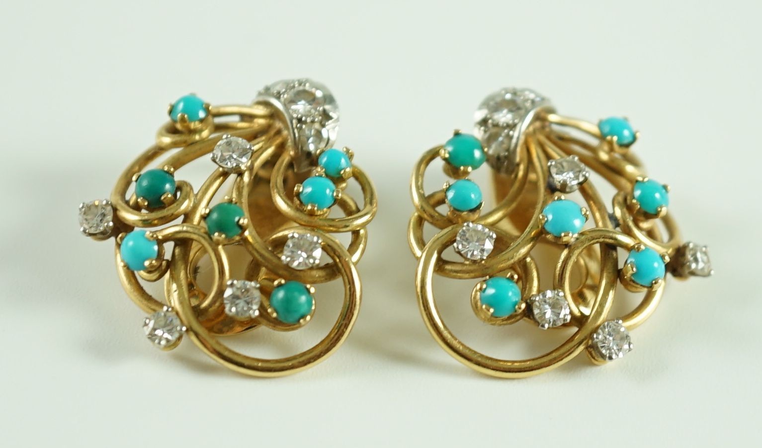 A pair of modern 18k gold diamond and turquoise cluster set scrolling ear clips